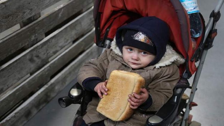 Photo News / Frightened child holds bread tightly in his hands, during the evacuation in Mariupol