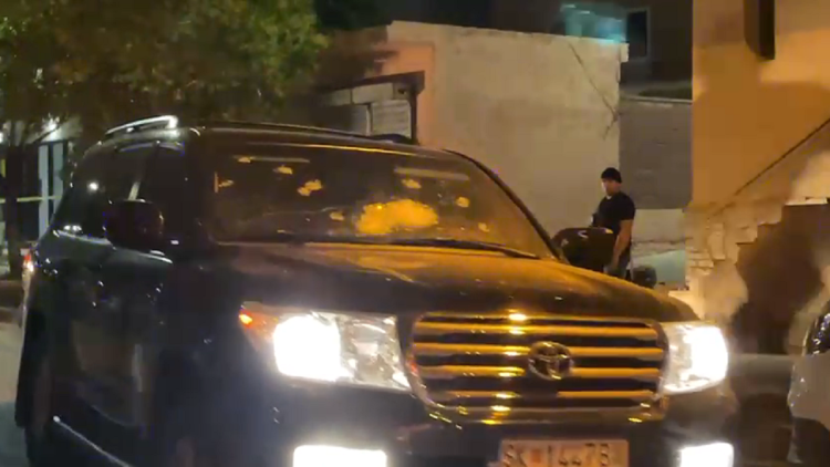 Armored car riddled with bullets, view from the scene of the assassination in Milot