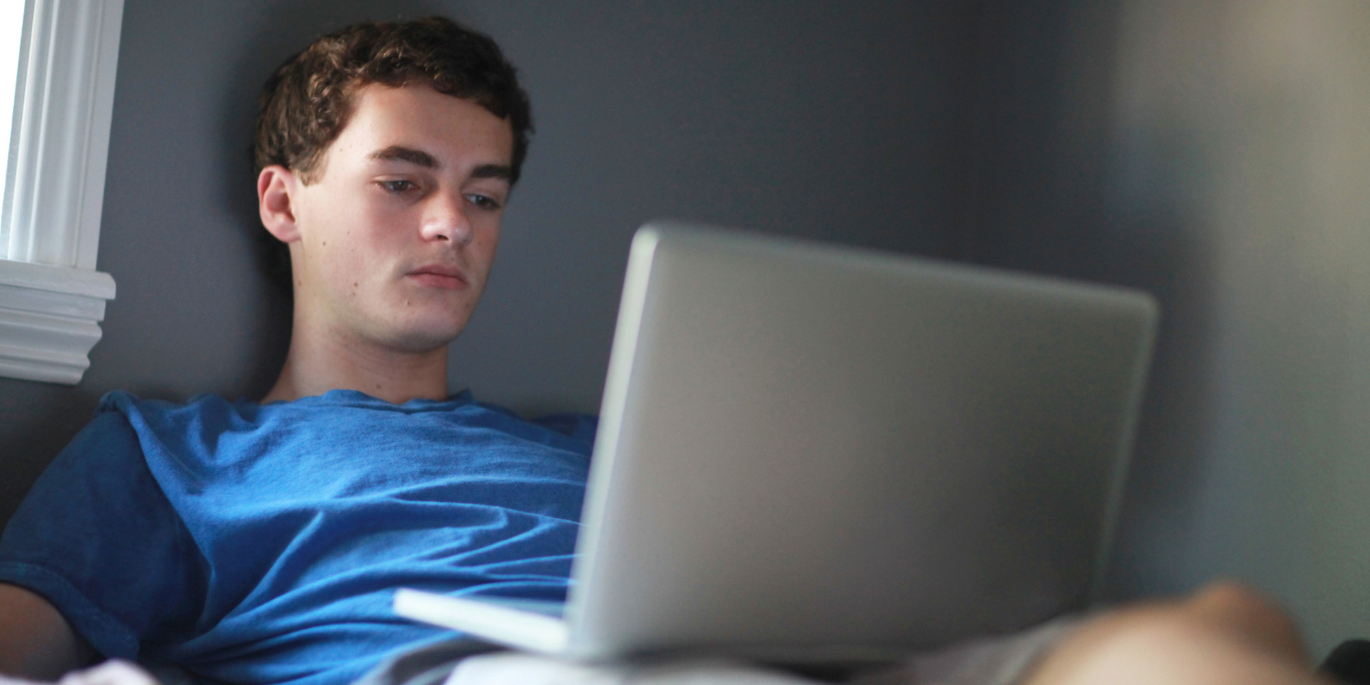 Teenage boy in room using laptop