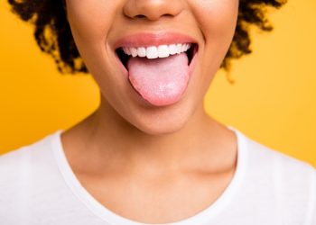 Cropped close up photo beautiful amazing she her dark skin lady beaming whitening toothy smile tongue out perfect mouth wear casual white t-shirt isolated yellow bright vibrant background.